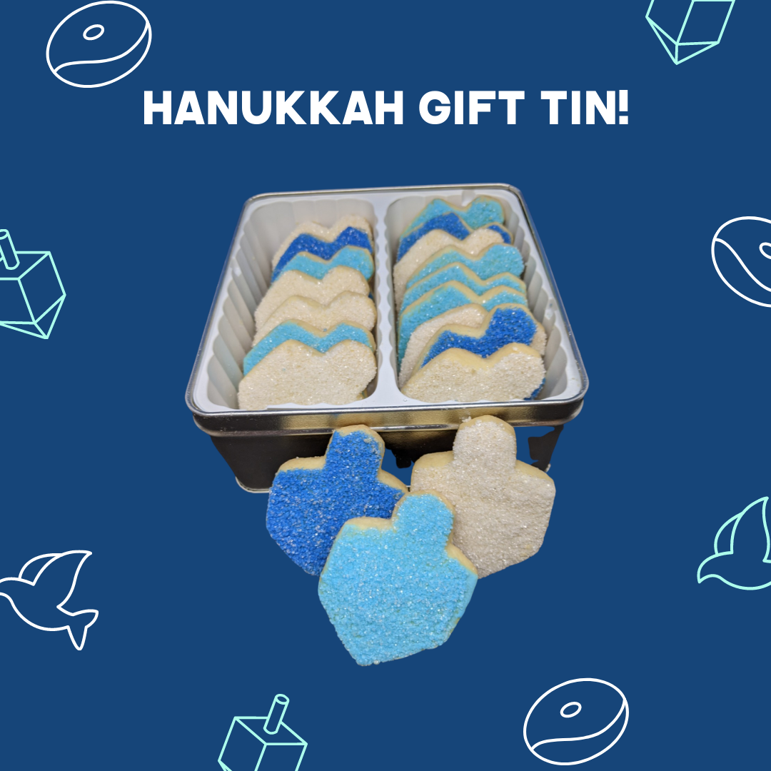A sleek square Hanukkah cookie gift tin containing 18 crispy blue and white sugared dreidel cookies, presented on a blue background with illustrations of a dreidel and a Hanukkah Menorah.