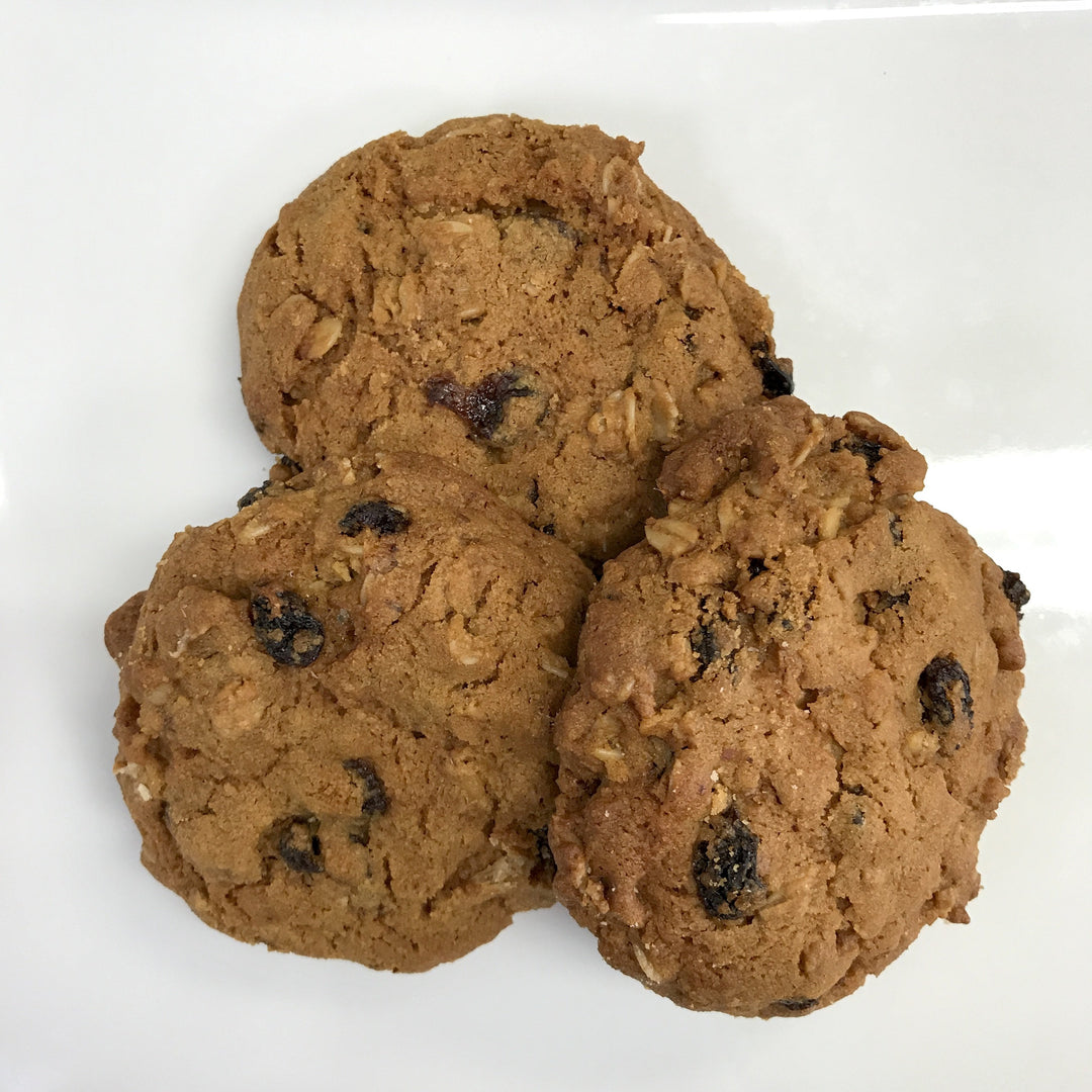 Three kosher oatmeal raisin cookies on a white surface.