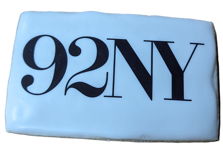 White cookie with '92NY' printed on it, placed on a wooden surface