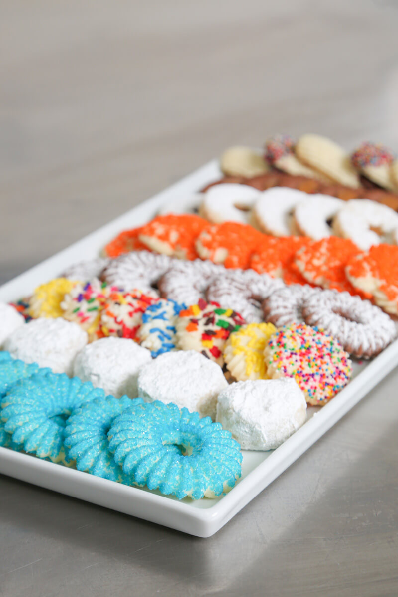 Tray of various kosher sugar cookies with sprinkles on a stainless steel counter top